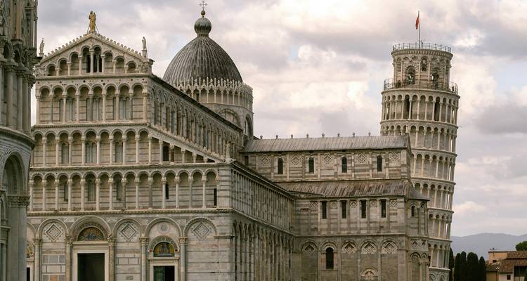 The Leaning Tower and Pisa Cathedral showcase Romanesque architecture under cloudy skies.