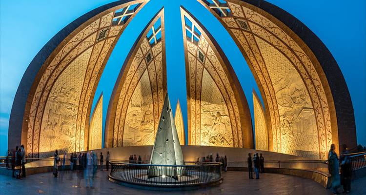 Beleuchtetes Pakistan-Denkmal mit kunstvollen goldenen Paneelen, die in der Dämmerung leuchten.