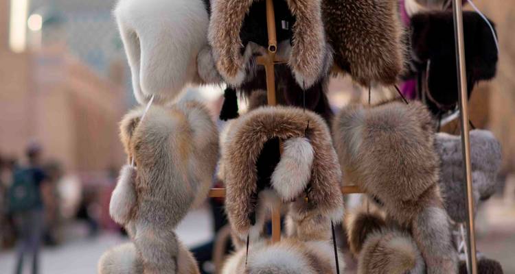 Étalage de chapeaux en fourrure duveteuse suspendus en rangées dans un stand de marché en plein air.