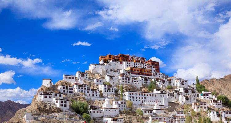 Großer weißer Klosterkomplex am Berghang, der sich gegen einen leuchtend blauen Himmel erhebt.