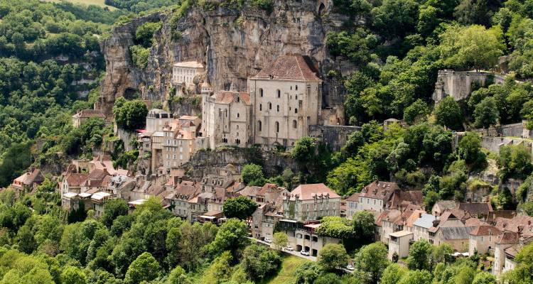 Mittelalterliches Klippendorf Rocamadour mit Steingebäuden, die über einem üppig grünen Tal gestapelt sind.