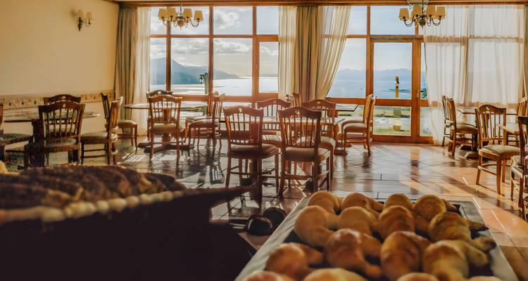 Gezellige hoteleetkamer met panoramische ramen met uitzicht over meer en bergen.