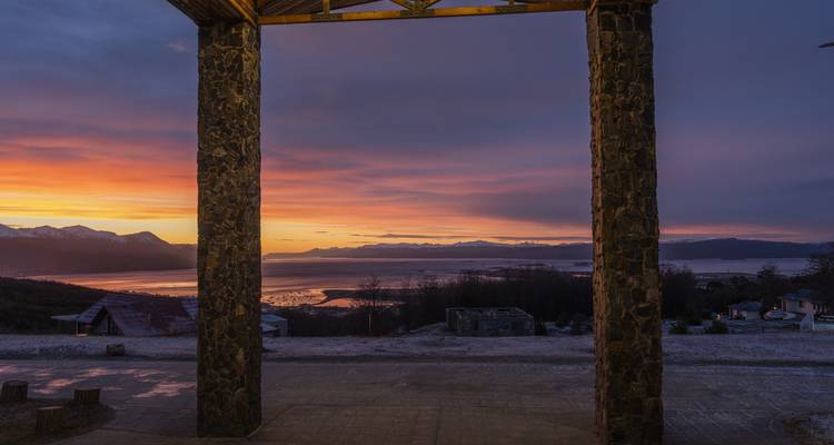 Omkaderd uitzicht van kleurrijke zonsopgang boven water gezien door een stenen boog.