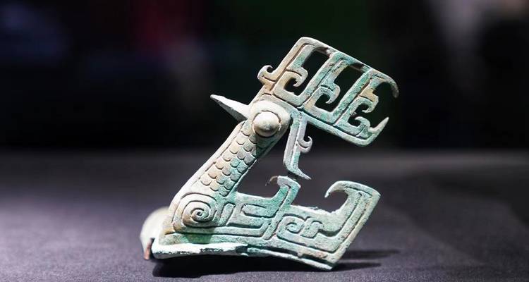 Ancient intricately carved bronze bird ornament displayed in a museum