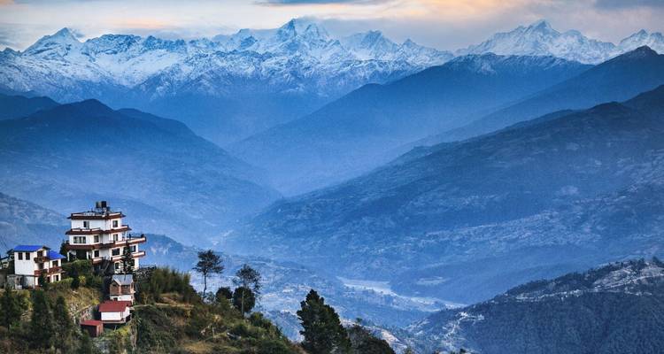 Dramatisches Himalaya-Panorama mit schneebedeckten Gipfeln und geschichteten blauen Tälern über einer Berghütte