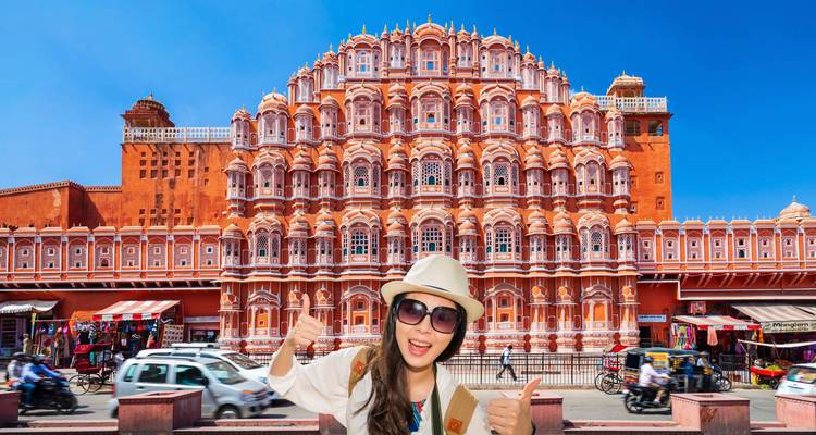 Traveller gives thumbs-up in front of Jaipur’s ornate pink Hawa Mahal under a clear blue sky.