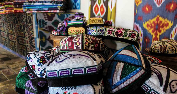 Pile de calottes perlées colorées et de tissus ikat à l'intérieur d'une boutique d'artisanat.