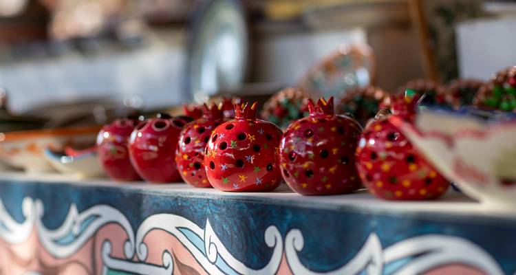 Rangée de figurines de grenades en céramique brillante sur un étal d'artisanat en flou artistique.