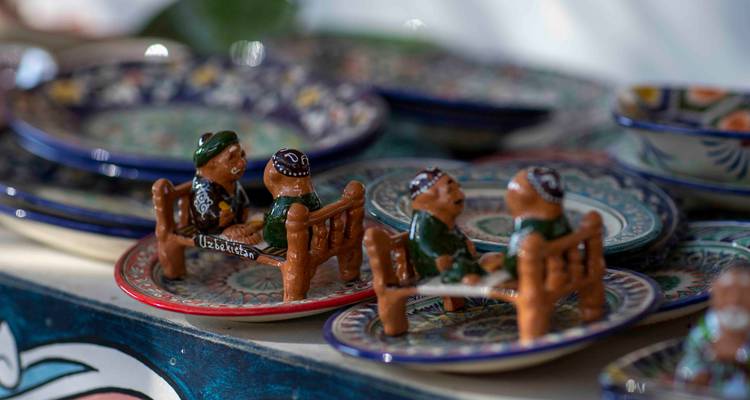 Petites assiettes en céramique peinte représentant des figurines ouzbèkes assises étiquetées 'Ouzbékistan'.