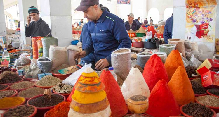 Marché aux épices intérieur animé avec des pyramides vibrantes d'épices colorées et des vendeurs servant la clientèle.