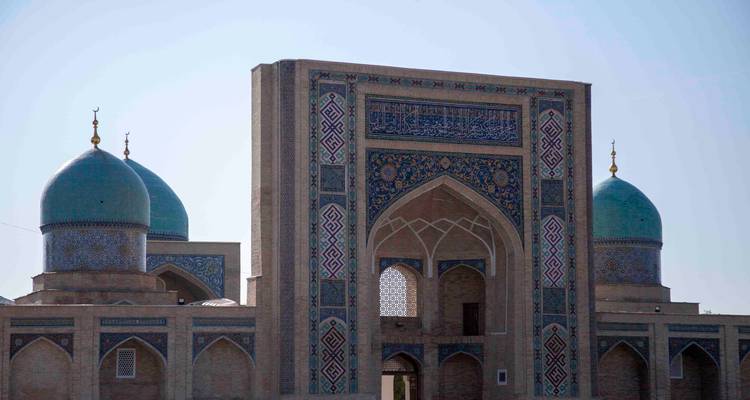 Vue latérale rapprochée du portail de Hazrati Imam et des coupoles turquoise sur fond de ciel lumineux.