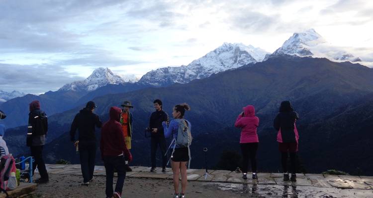 Group of trekkers admire sunrise views over the Annapurna massif from Poon Hill viewpoint.