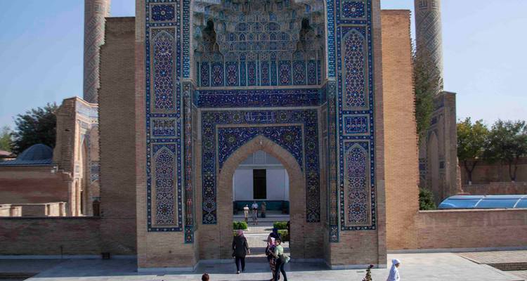 Les visiteurs se rassemblent à l'entrée carrelée de Gur-e Amir, encadrée par de hauts minarets.