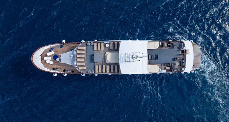 Top-down view of a yacht showing decks, sunbeds and the surrounding dark blue water.