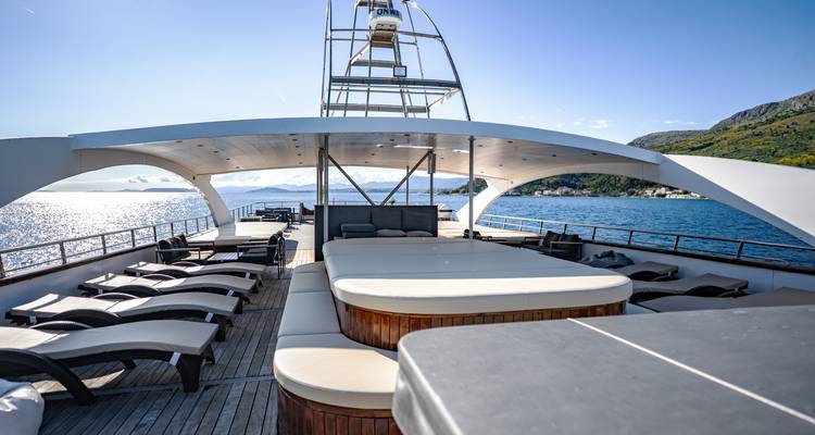 Yacht sundeck featuring a hot tub, loungers and sweeping sea views.