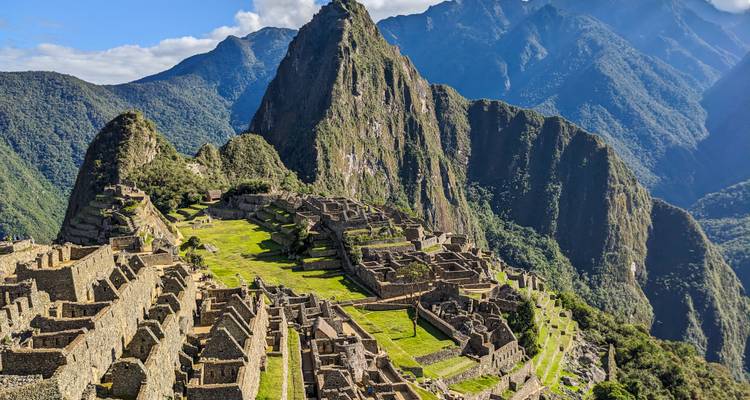 Iconisch uitzicht over de oude stenen terrassen en dramatische bergachtergrond van Machu Picchu onder helder zonlicht.