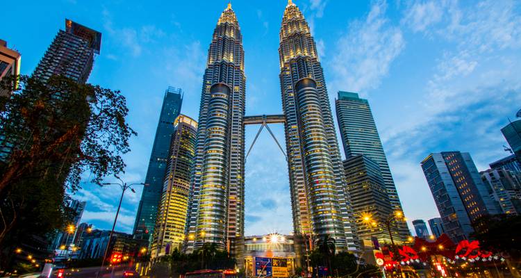 Torres Petronas y rascacielos circundantes brillantemente iluminados contra un cielo nocturno azul profundo en Kuala Lumpur.