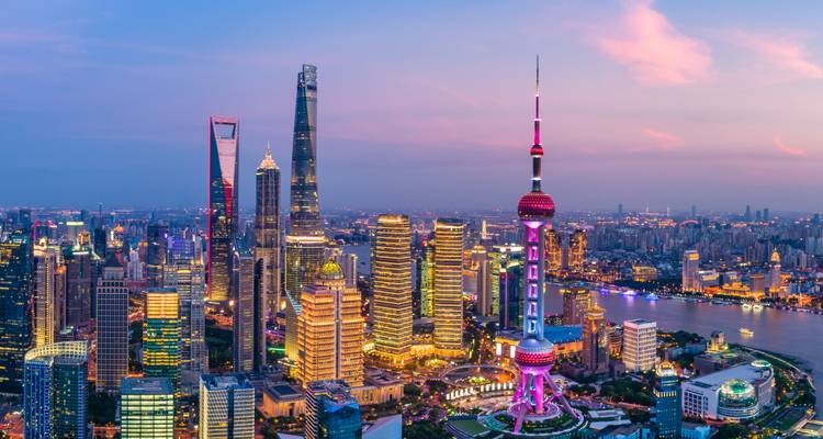 Panorama éblouissant du crépuscule des gratte-ciel illuminés de Shanghai et de la rivière sous un ciel rose du soir.