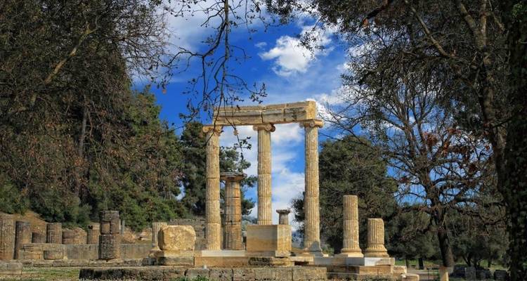 Ruïnes van het cirkelvormige Philippeion monument omlijst door bomen in het antieke Olympia