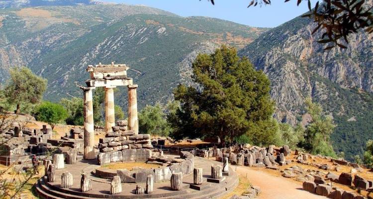 Tholos van Delphi omlijst door olijfbomen en ruige bergachtergrond