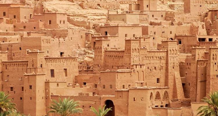 Close-up van de terracotta torens en muren van Aït Benhaddou's versterkte ksar met palmbomen eronder