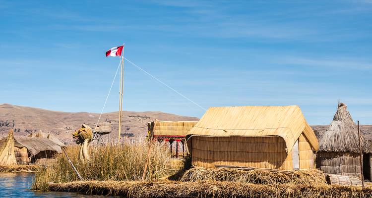 Cabaña tradicional de totora con bandera peruana en las islas flotantes de los Uros en el lago Titicaca.