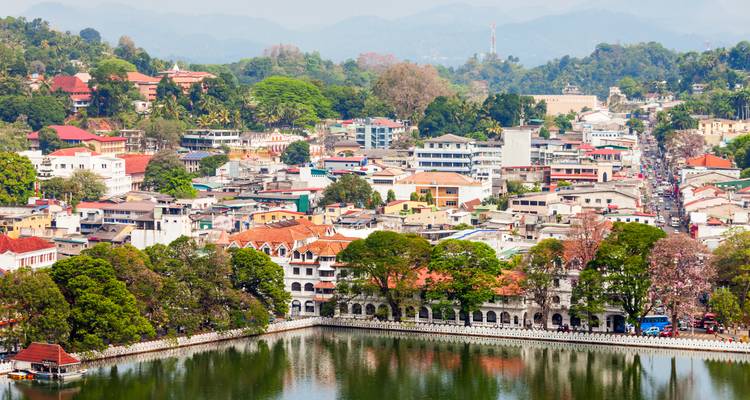 Luchtfoto van de stad Kandy met meer, gebouwen met rode daken en weelderige heuvels.