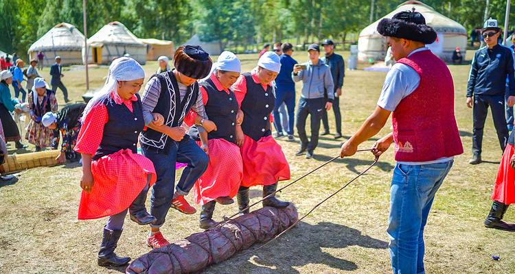 Lugareños en vestimenta tradicional juegan un animado juego de tirar del tobillo durante el festival del campamento de yurtas