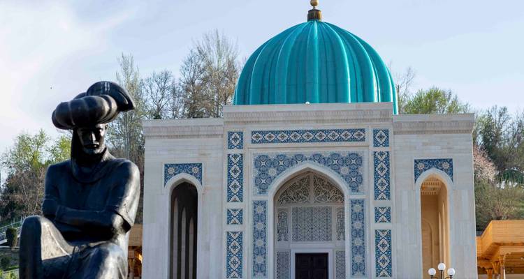 Vue rapprochée d'une statue en bronze située devant un sanctuaire orné de carreaux bleus surmonté d'un dôme turquoise