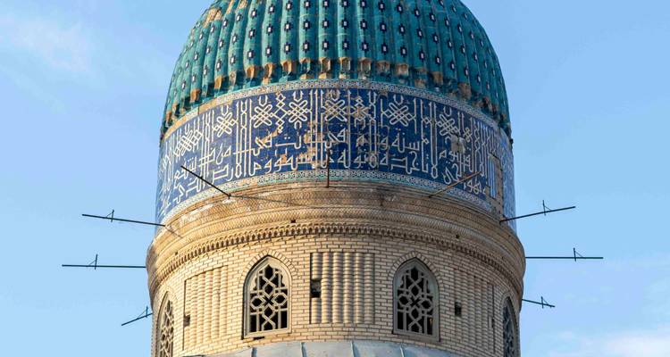 Gros plan détaillé d'un dôme en mosaïque turquoise décoré de calligraphie arabe et de briquetage