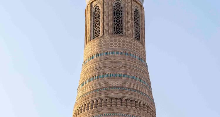 Grand minaret aux motifs complexes se détachant sur un ciel du soir bleu pâle