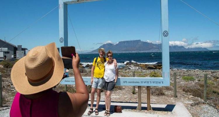 Tourist snaps a photo of a smiling couple framed by a giant picture frame with Table Mountain behind.