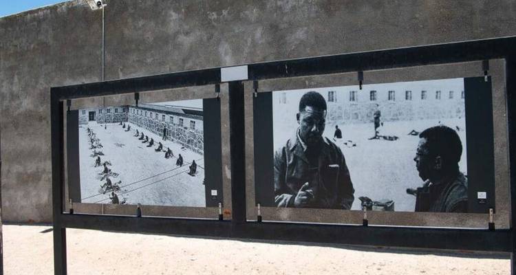Outdoor display boards showing historical black-and-white prison photographs against a concrete wall