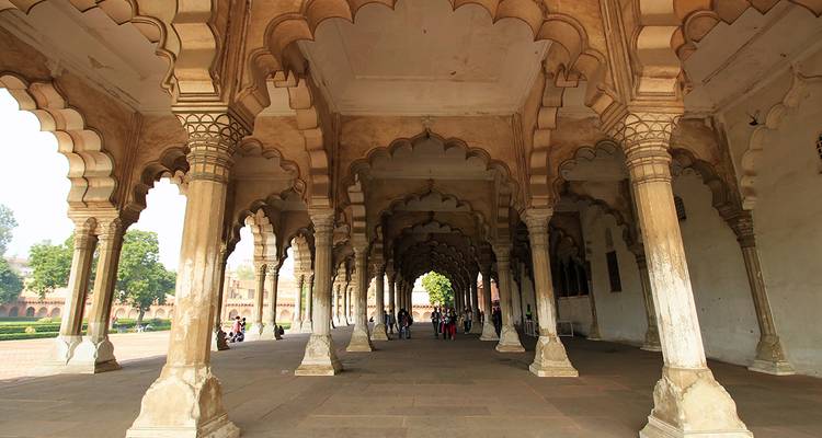 Les visiteurs se promènent à travers la grande colonnade voûtée d'un fort de l'époque moghole, ses piliers de grès richement décorés.