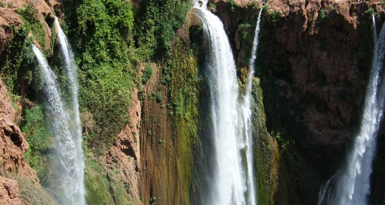 Krachtige meerlaagsе Ouzoud waterval die naar beneden stort over rode rotsklіffen weelderig begroeid met groene vegetatie.