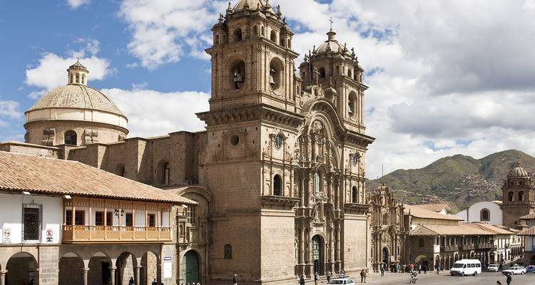 Conjunto de catedral de piedra histórica que domina la plaza central de Cusco con arcadas coloniales y cerros andinos al fondo