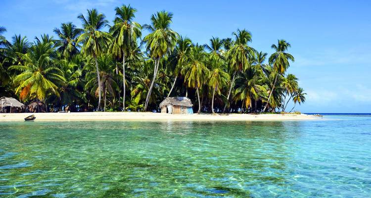 Een klein eilandje met wit zand omzoomd met hoge kokospalmen verheft zich uit kristalhelder turquoise water in de San Blas-archipel.