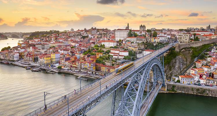 Le pont Dom Luís I s'étend sur le fleuve Douro vers le centre historique de Porto au coucher du soleil