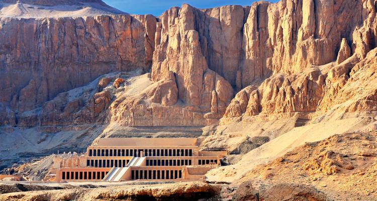 Terrassentempel der Hatschepsut vor den aufragenden ockerfarbenen Klippen in Luxors Wüste.