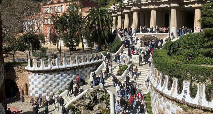 Multitudes explorando las grandes escalinatas y columnatas del Parque Güell en un día soleado