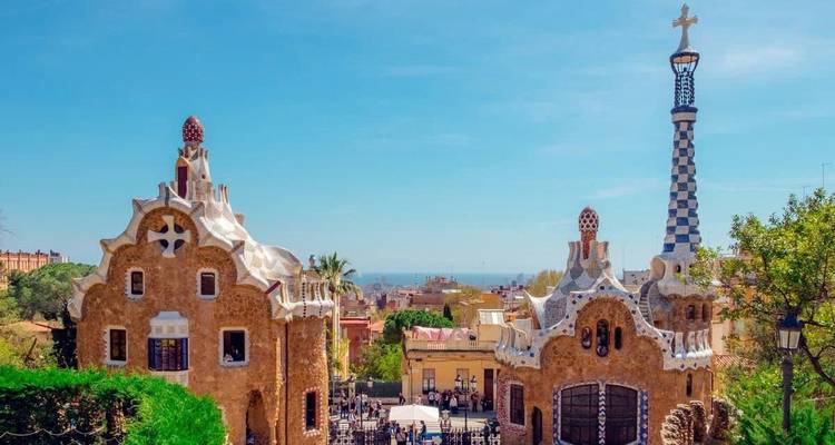 Casitas de pan de jengibre de cuento de hadas de Park Güell con vista lejana al mar bajo un cielo despejado