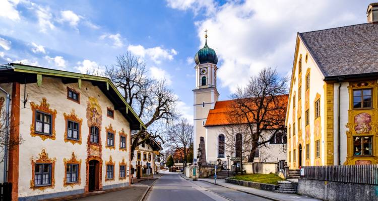 Maisons aux fresques colorées et clocher à bulbe dans une rue pittoresque d'Oberammergau