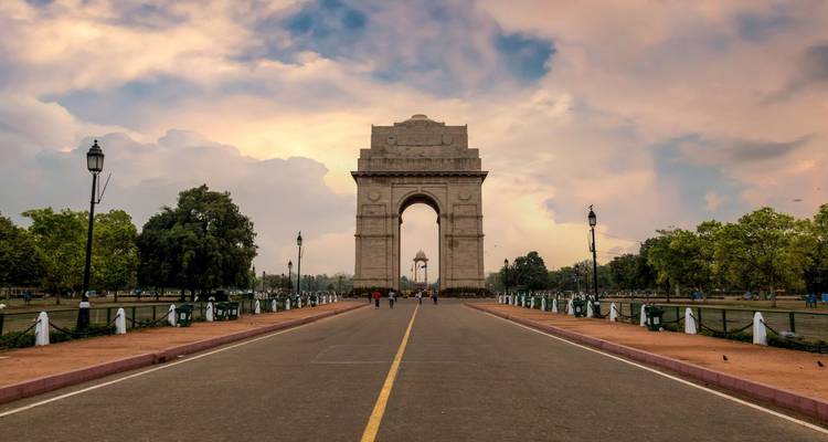 India Gate in Neu-Delhi, aufgenommen vom Zentrum einer leeren Allee bei Sonnenaufgang.