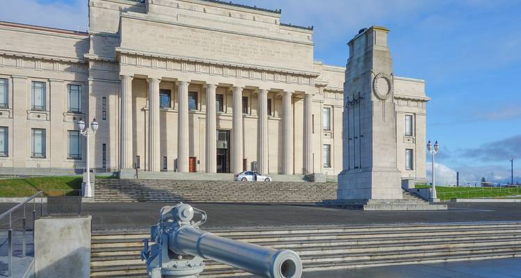 Neoklassiek Auckland War Memorial Museum en cenotaaf onder blauwe hemel.