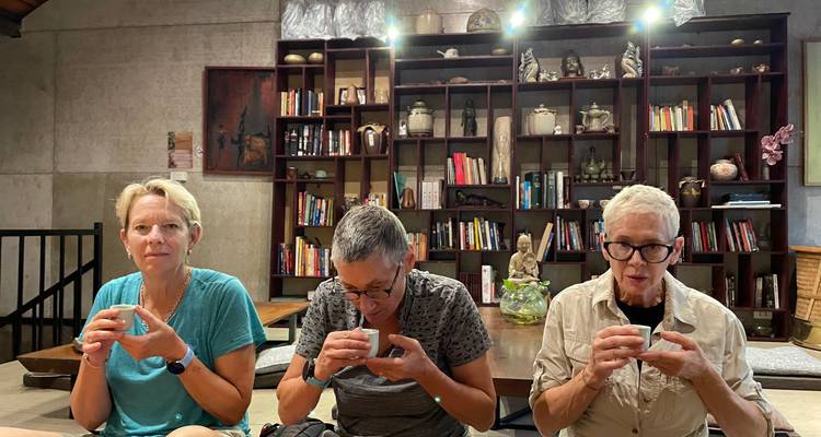 Trois voyageurs sont assis dans un café au style bibliothèque confortable en sirotant de petites tasses de café vietnamien.