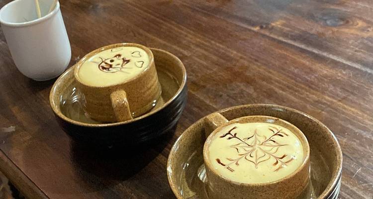 Des tasses de café aux œufs artistiquement présentées avec des motifs en cacao sur une table en bois.