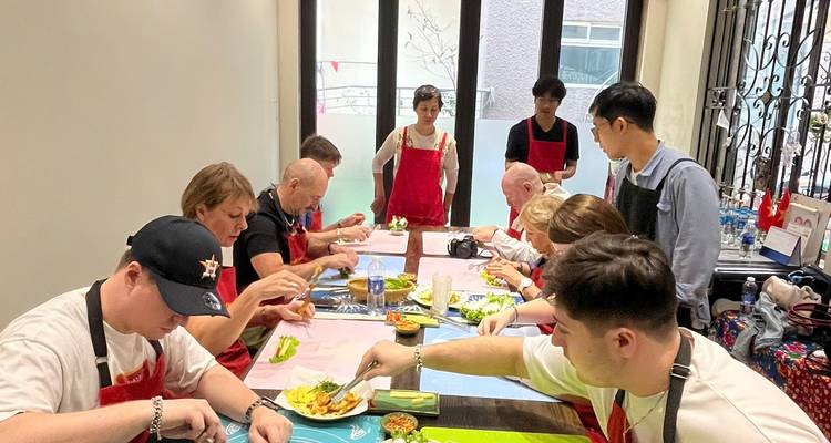 Les voyageurs portant des tabliers apprennent à préparer des plats vietnamiens lors d'un cours de cuisine interactif.