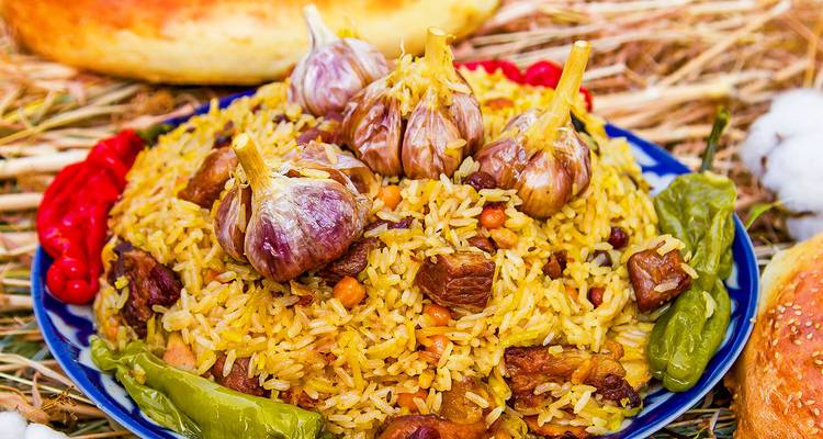 Hartige schotel van aromatische rijstpilaf gegarneerd met hele knoflookbollen en paprika's