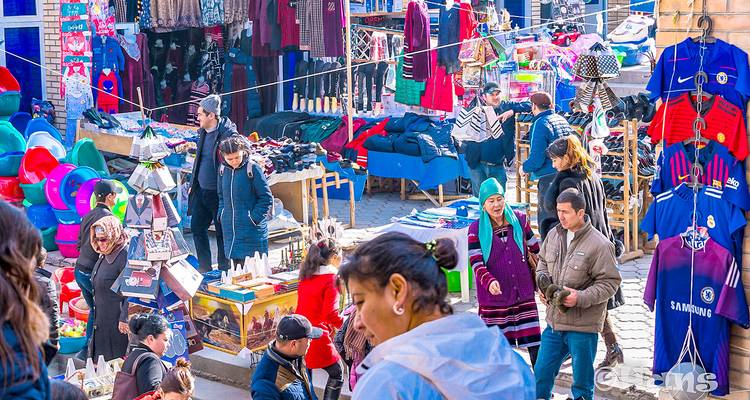 Drukke buitenmarkt vol met kleurrijke kramen, winkelende mensen en lokale verkopers
