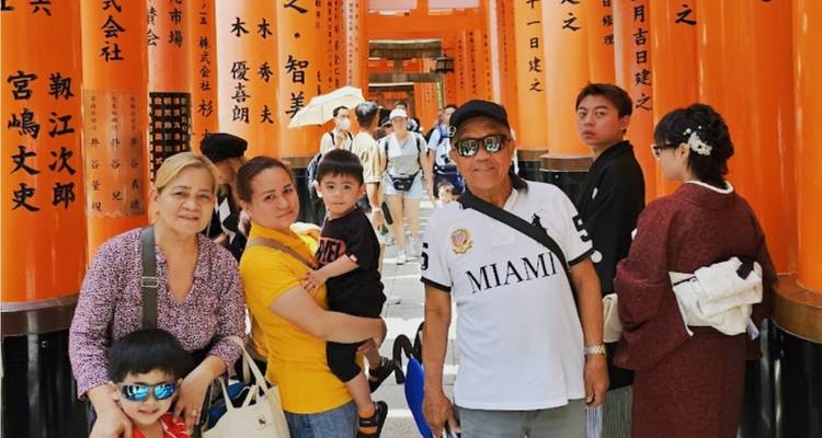 Een meergenerationenfamilie poseert te midden van de levendige oranje torii-tunnels van het Fushimi Inari-heiligdom.